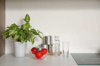 Çiçek, domatesli kase ve beyaz mutfak tezgahında bir şişe su.