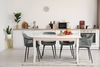 Yemek masasında meyve sepeti olan modern mutfağın içi.