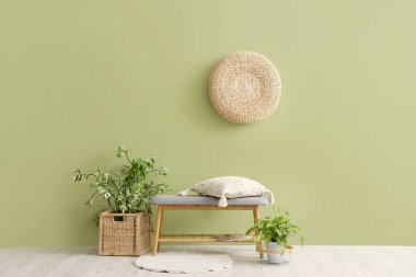 Yastıklı gri bank ve yeşil duvarın yanında bitkiler