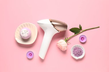 Banyo malzemeleri, mumlar ve pembe arka planda gül çiçekli modern fotoepilatör.