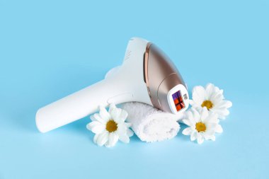 Banyo havlusu ve mavi arka planda güzel çiçekleri olan modern fotoepilatör.