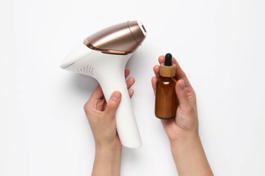 Modern fotokopi makinesi ve beyaz arka planda bir şişe kozmetik yağı olan kadın elleri.