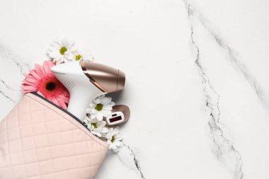 Modern fotoepilatorlu çanta, eklenti ve beyaz arka planda güzel çiçekler.