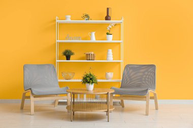 Gri sandalyeli ve turuncu duvarlı modern raf ünitesi.