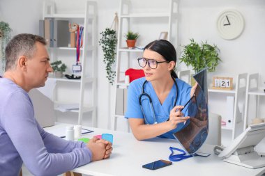 Kadın doktor klinikteki hastaya röntgen taraması gösteriyor.