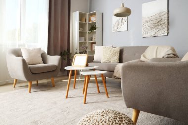 Modern oturma odasının içinde gri kanepe, koltuklar ve sehpanın üzerinde boş fotoğraf çerçevesi.
