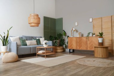 Modern oturma odasının içinde gri kanepe, yeşil katlanmış ekran ve kahve masası.