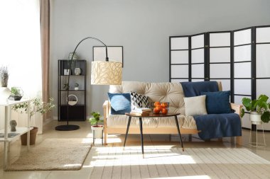 Modern oturma odasının içinde beyaz kanepe, sehpa ve standart lamba var.