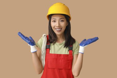 Bej arka planda kabloları olan genç bayan elektrikçi.