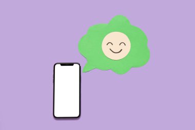 Boş ekranlı cep telefonu ve eflatun arkaplanda gülen yüzlü konuşma balonu