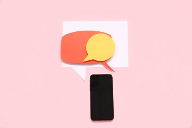 Boş ekranlı cep telefonu ve pembe arka planda konuşma baloncukları