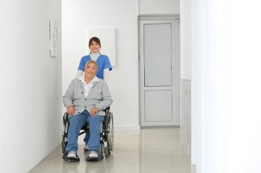 Tekerlekli sandalyedeki yaşlı kadın, bakıcısı içeride.