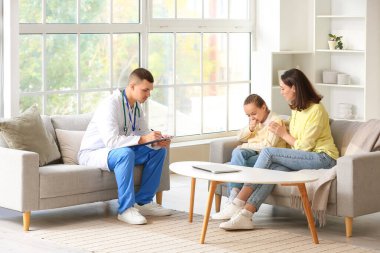 Erkek doktor, küçük kız ve annesiyle çalışıyor.