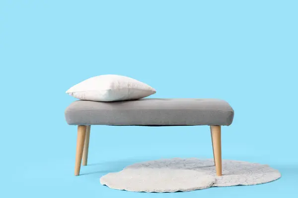 Grey bench with cushions and rugs on blue background