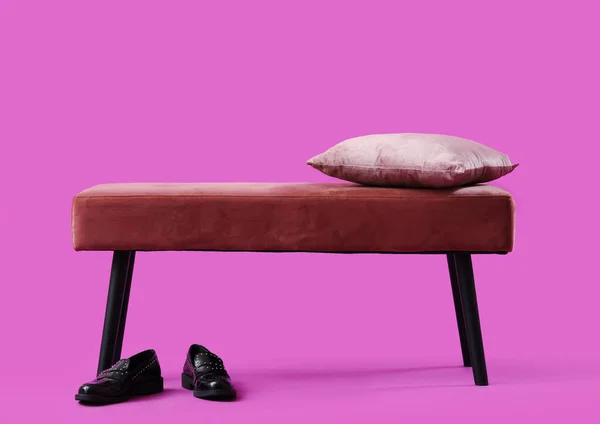 Bench with cushion and shoes on pink background