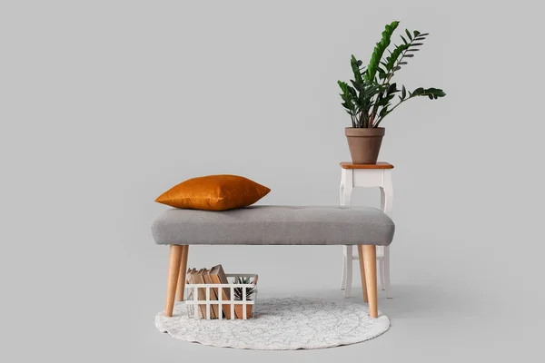 Bench with cushion and houseplant on grey background