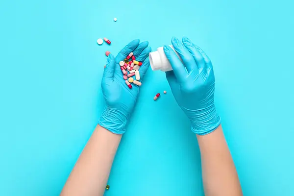 Doctor with pills on blue background
