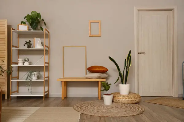 Interior of modern living room with wooden bench, shelving unit and houseplants