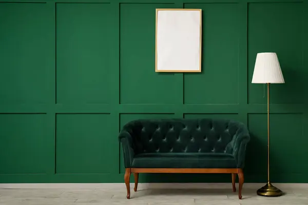 Modern green sofa with lamp and frame near green wall