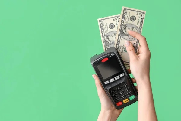 Female hands with payment terminal and money on green background