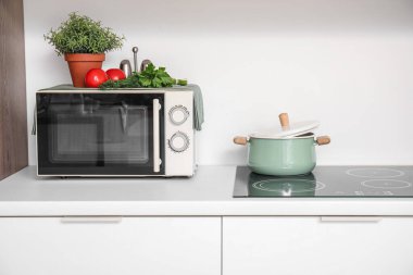 Modern mikrodalga fırın ve mutfak tezgahında pişirme kabı.