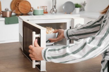 Modern mutfakta mikrodalga fırında patlamış mısır yapan kadın.