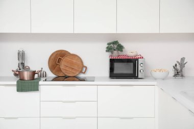 Mikrodalga fırını, elektrikli soba ve beyaz tezgahlı mutfak malzemeleri.