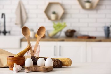 Yumurta, taze ekmek ve mutfak masasındaki mutfak aletleri.