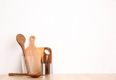 Mutfak aletleri beyaz duvarın yanındaki ahşap masada.