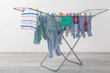 Çamaşır odasındaki kurutucuya asılı temiz bebek kıyafetleri.