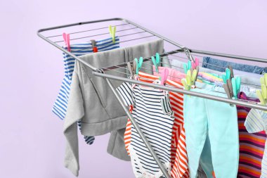 Leylak duvarının yanındaki kurutucuda asılı temiz bebek kıyafetleri.