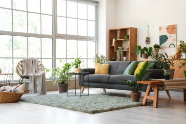 Rahat gri kanepe ve çiçeklerle aydınlık oturma odasının içinde.