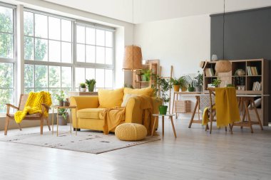 Sarı kanepeli ve çiçekli modern oturma odasının içi.