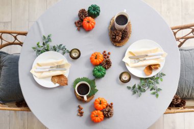 Balkabakları, yanan mumlar ve yapraklarla sonbahar masası.