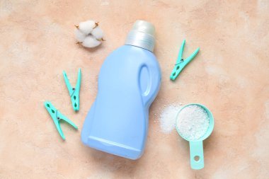 Pamuk çiçekli farklı çamaşır deterjanları ve bej renkli grunge arkaplanda mandallar.