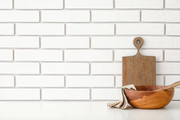 Kitchen utensils on table near white brick wall