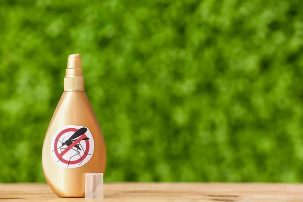 Spray bottle of mosquito repellent on table outdoors