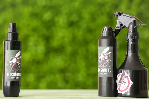 Spray bottles of mosquito repellent on table outdoors