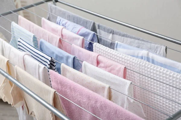 Clean towels and baby clothes hanging on dryer, closeup