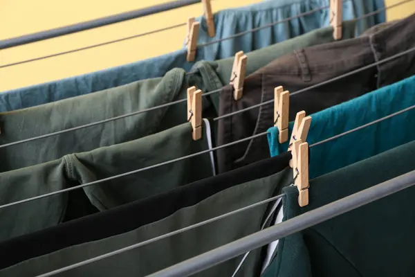 Clean green clothes hanging on dryer, closeup