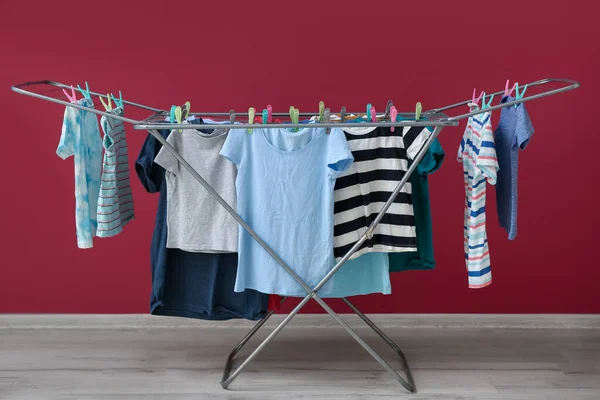 Clean clothes hanging on dryer near red wall