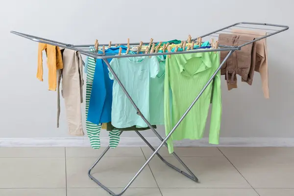 Clean clothes hanging on dryer near white wall