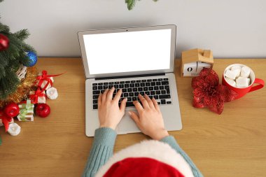 Noel arifesinde ofiste dizüstü bilgisayarla çalışan bir kadın.