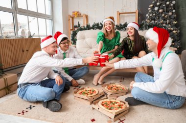 Bir grup genç arkadaş içki ve pizzayla Noel 'i ev partisinde kutluyorlar.