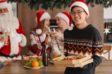 Noel partisinde pizzalı genç bir Asyalı.