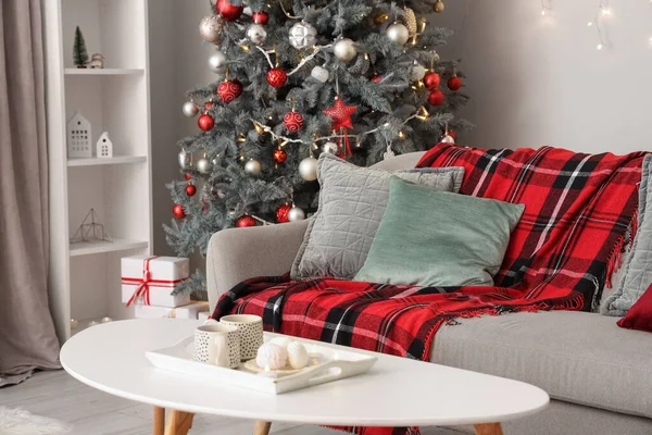 Interior of living room with sofa, Christmas tree and table