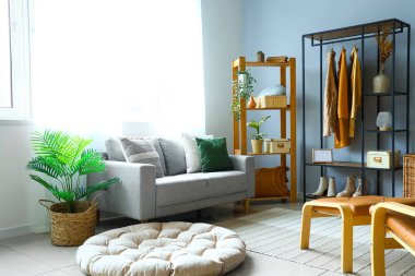 Rafların, kıyafetlerin ve kanepenin olduğu aydınlatma odasının içinde.