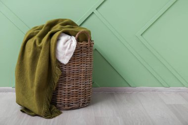 Yeşil duvarın yanında yeni yumuşak battaniyelerle dolu sepet.