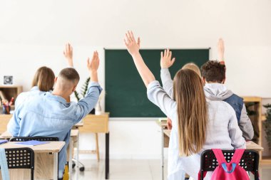 Sınıf arkadaşları cevap vermek için el kaldırıyor.