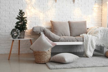 Oturma odasının içinde Noel ağacı, kanepe ve parıldayan ışıklar var.
